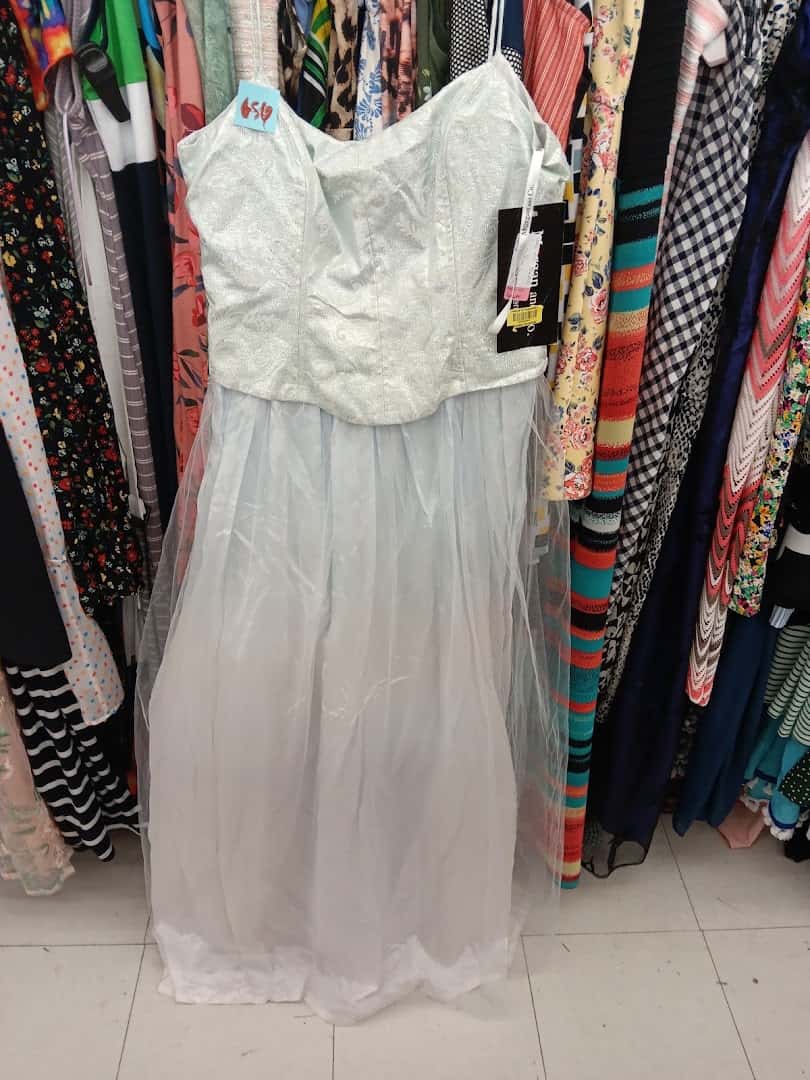 White dress on a hanger among clothing racks at Thrift Giant in Dallas