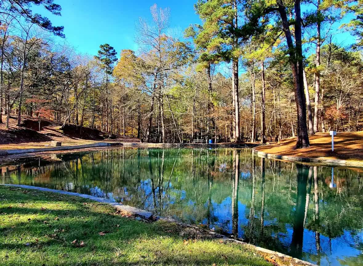 Clear spring-fed pond reflecting the pines at Camp Tonkawa Springs in Garrison, Texas