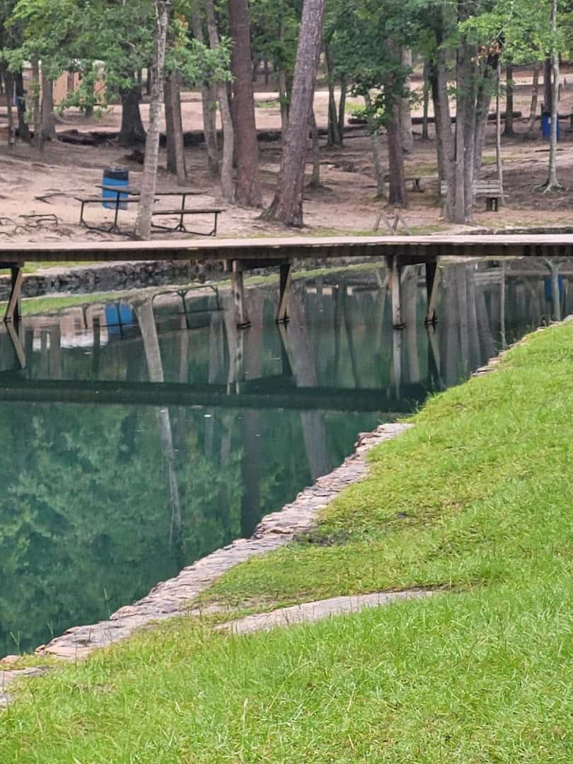 Stone-lined bank of the clear spring-fed pond at Camp Tonkawa Springs, Texas