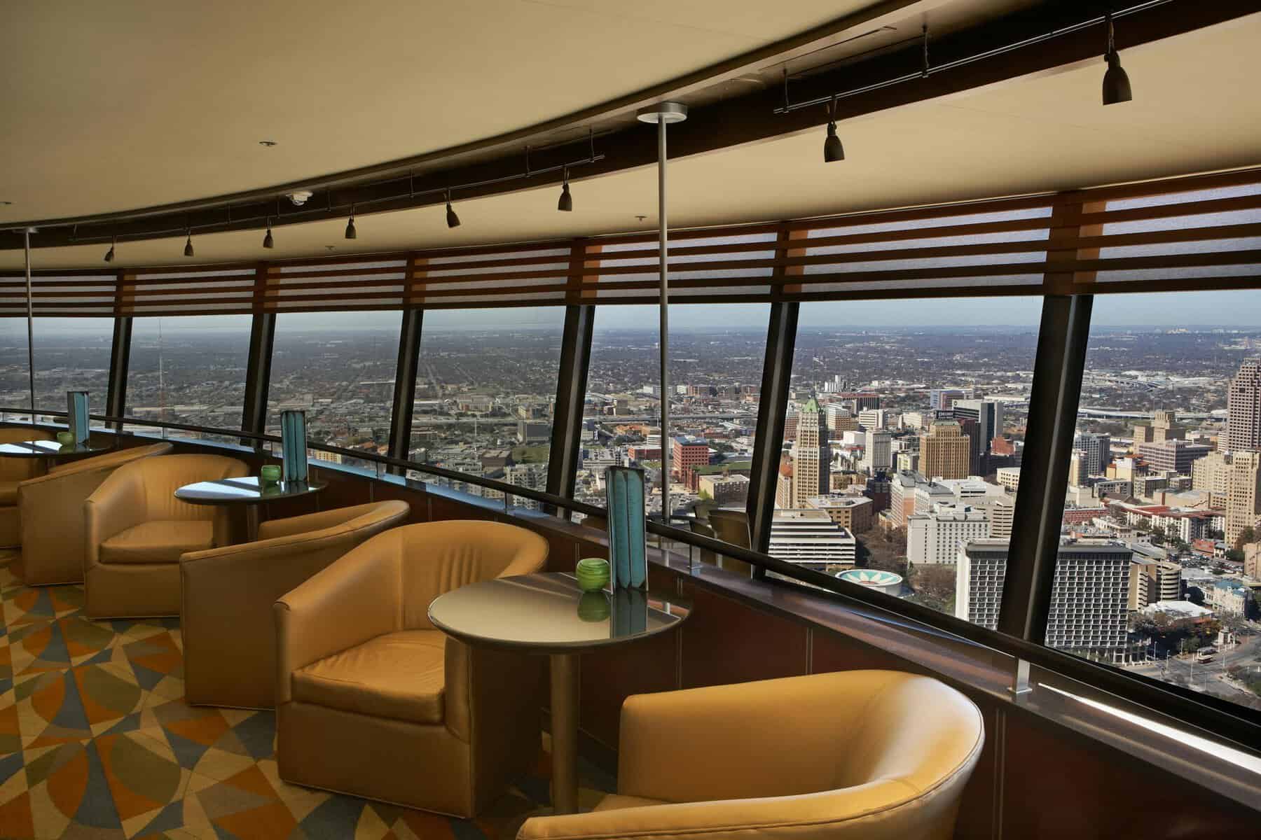 Lounge armchairs beside floor to ceiling windows overlooking downtown San Antonio at the Tower of the Americas