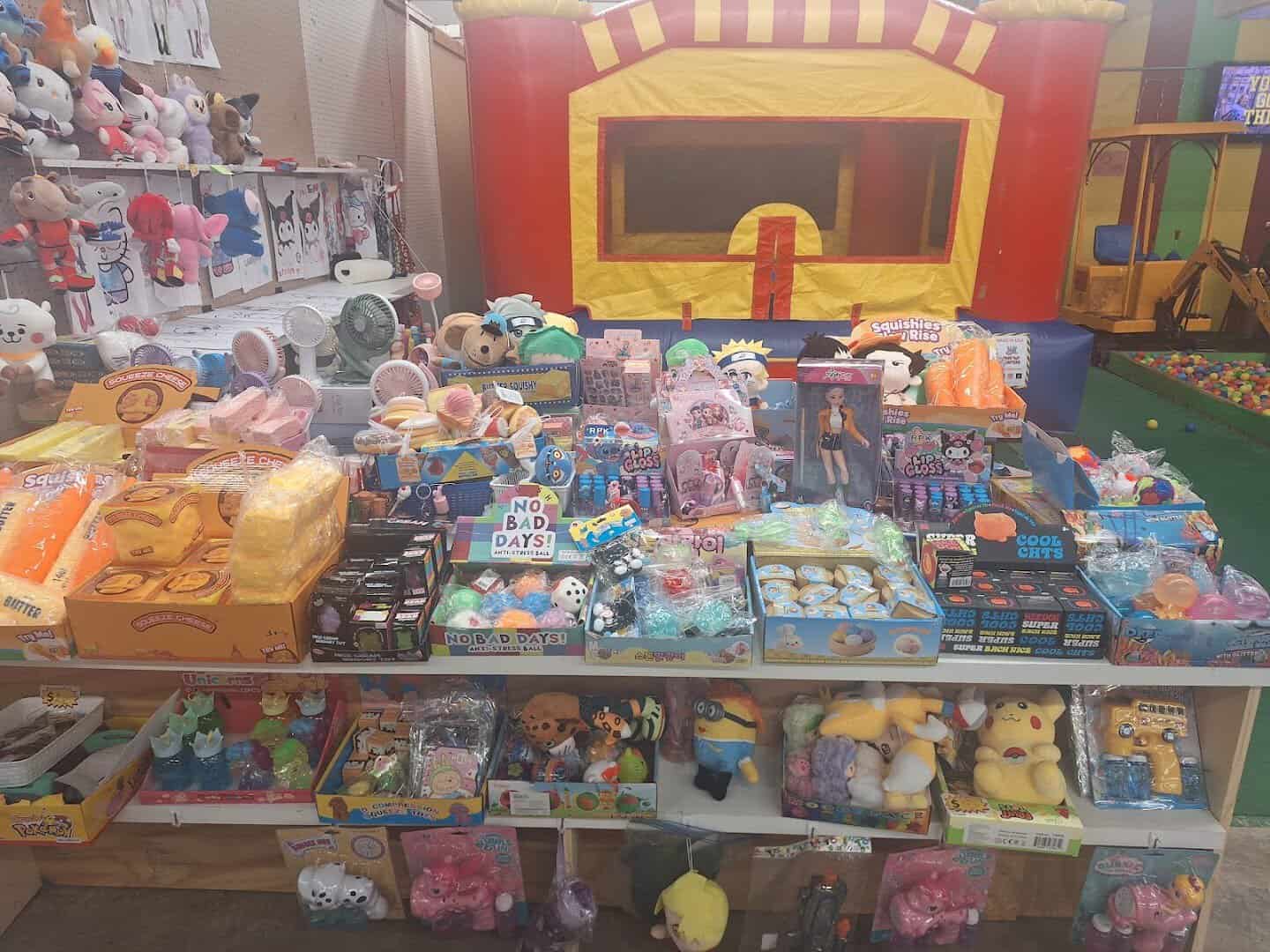 A toy booth stocked with plush toys in front of a bounce house at Cole's flea market in Pearland, Texas
