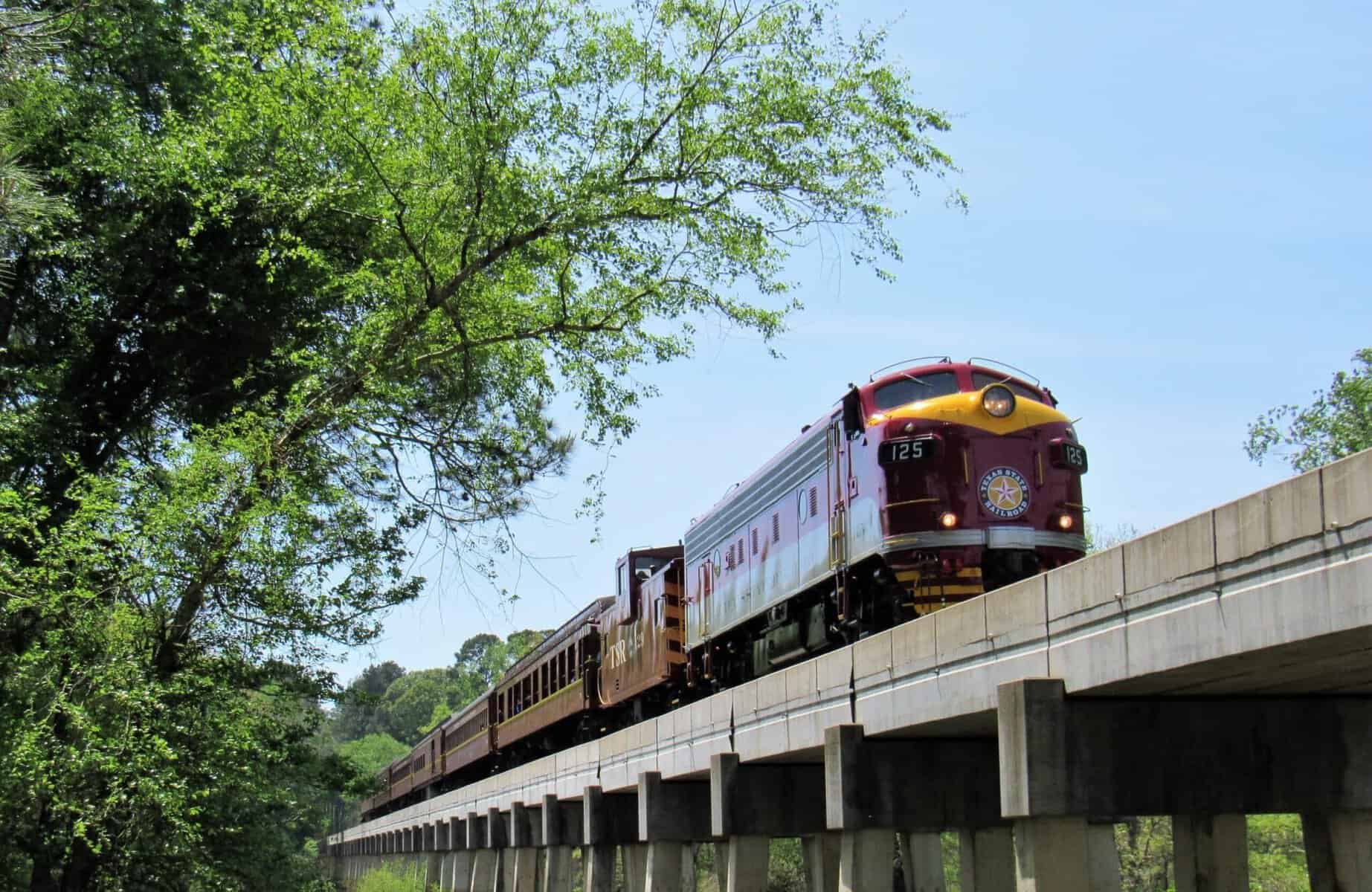 Texas State Railroad train crossing a steel trestle bridge over the forest