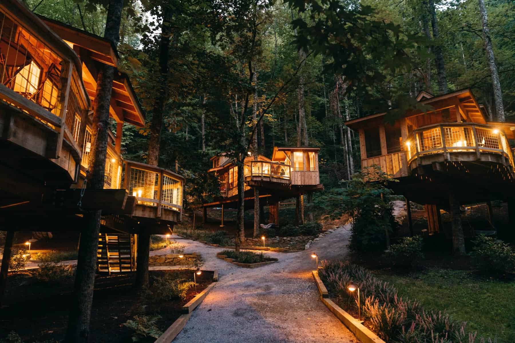 Luxury treehouses glowing at dusk in the woods at Treehouse Grove in Tennessee
