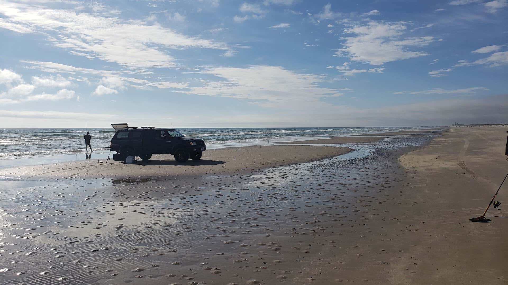 Truck driving on the packed sand beach at Mustang Island State Park, Texas