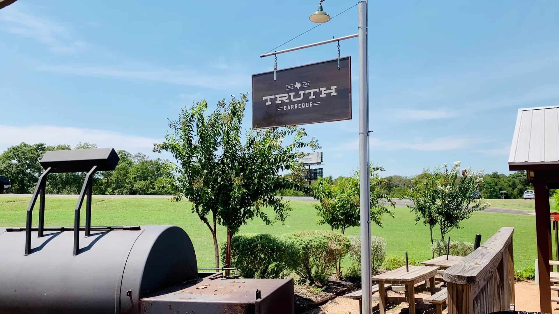 Offset smoker and sign outside Truth Barbeque in Brenham, Texas