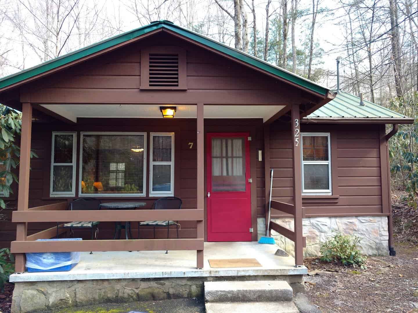 Wooden cabin with a red door and front porch at Twinbrook Resort in Maggie Valley, North Carolina