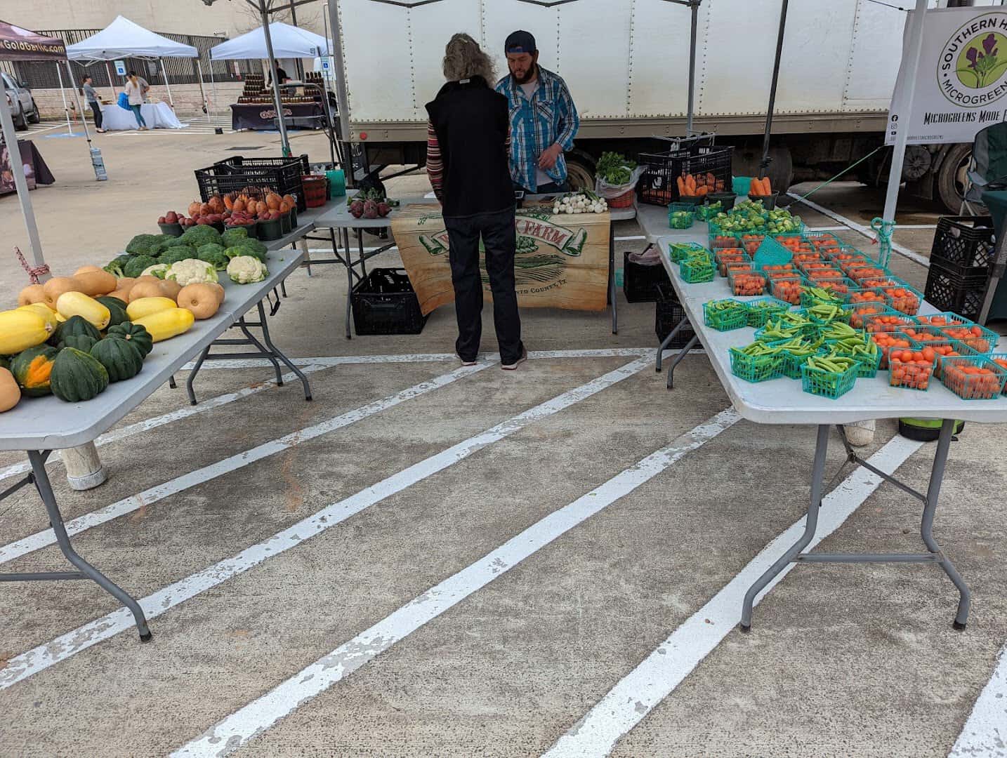 Vendor selling fresh produce from tables at Urban Harvest Farmers Market in Houston