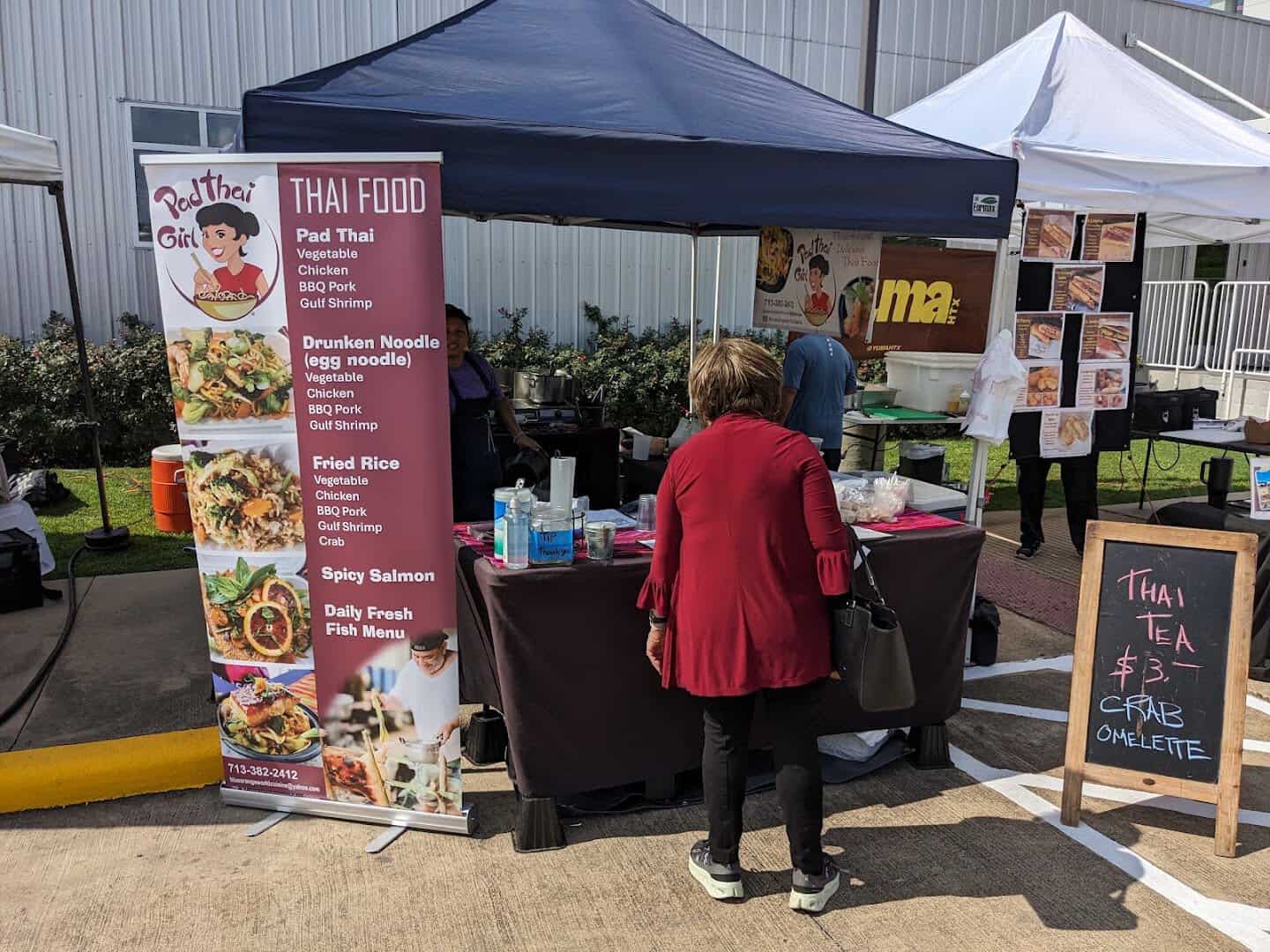 Prepared-food vendor stall with a posted menu at Urban Harvest Farmers Market in Houston