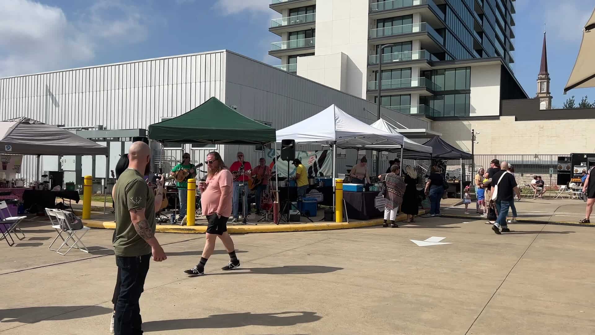 Shoppers walking the aisle of white vendor tents at the Saturday Urban Harvest Farmers Market in Houston