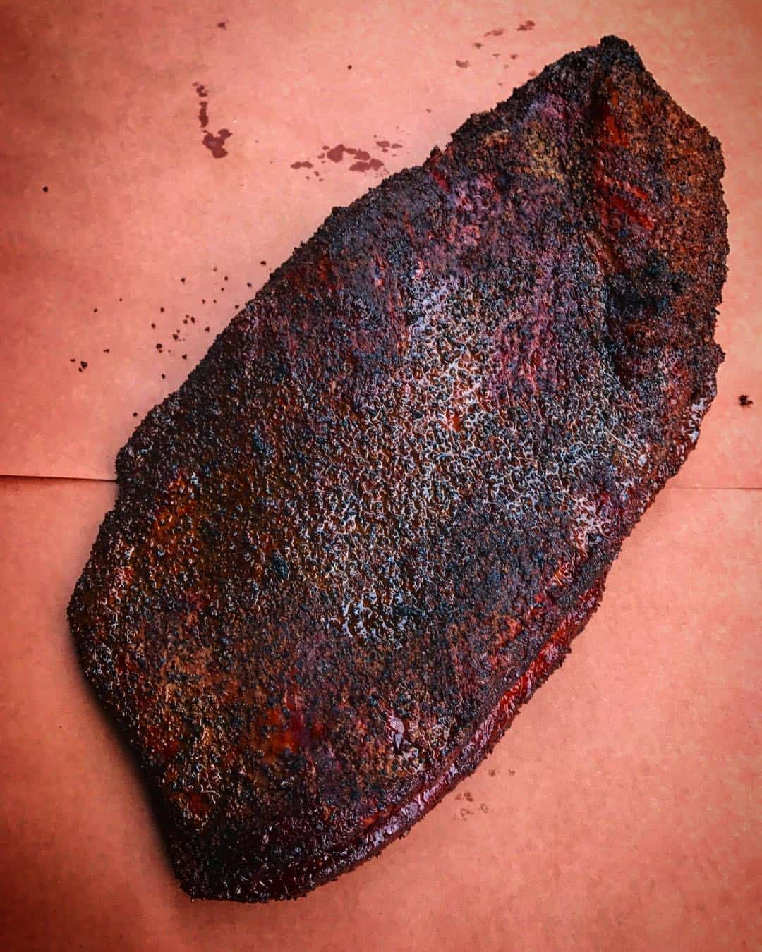 Smoked brisket with a thick bark on butcher paper at Victorian's Barbecue in Mart, Texas