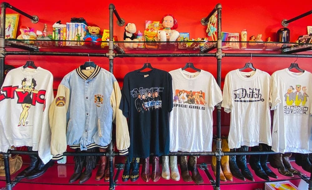 Vintage band tees displayed on a red wall at Leopard Lounge in Houston
