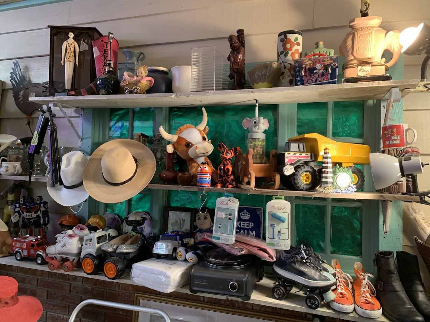 A shelf of vintage curios, toys and hats at an indoor booth in Cole's Antique Village, Pearland, Texas