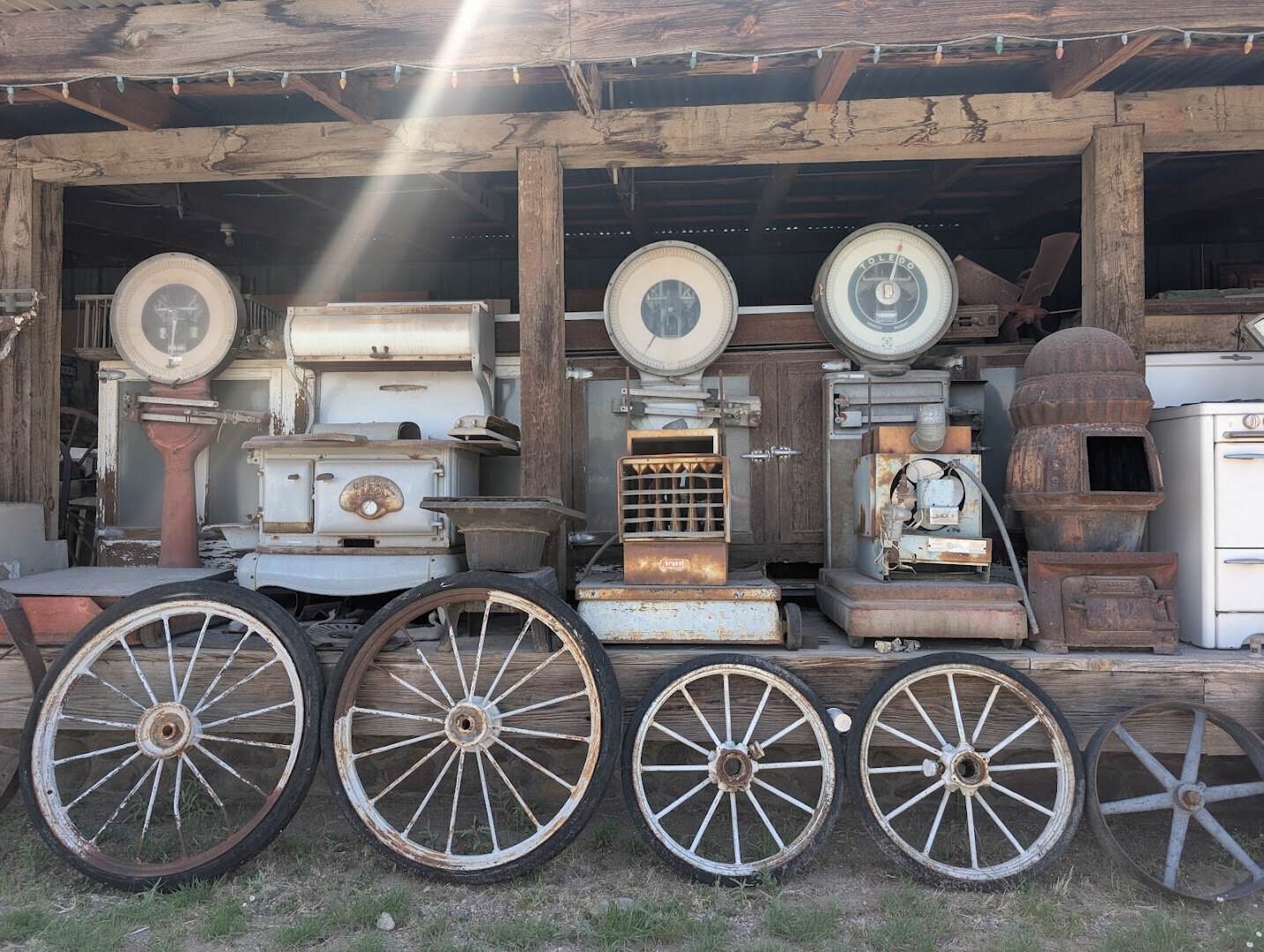 Wagon wheels, enamelware and vintage stoves in the outdoor salvage lot at The Whoopee Bowl Antique Mall in Canutillo, Texas