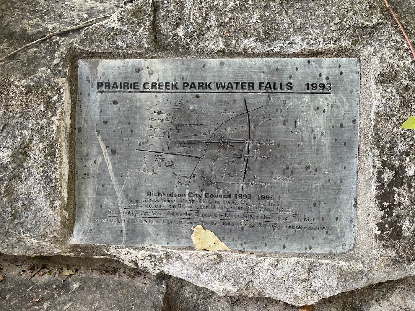 Stone plaque dating the Prairie Creek Park waterfall to 1993 in Richardson, Texas
