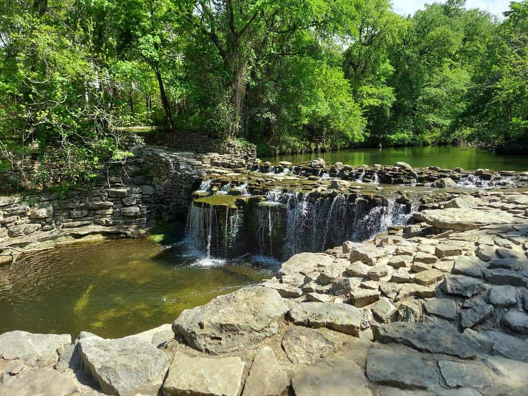 Water spilling over stone ledges at Prairie Creek Waterfall in Richardson, Texas