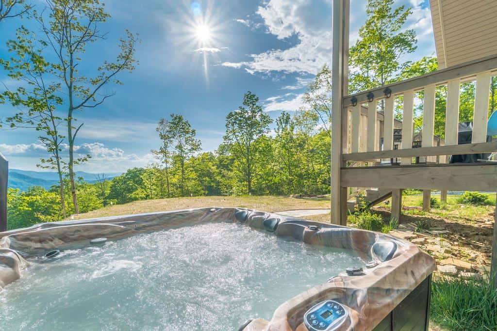 Deck hot tub overlooking the blue Smoky Mountains at Watershed Cabins in Bryson City, North Carolina