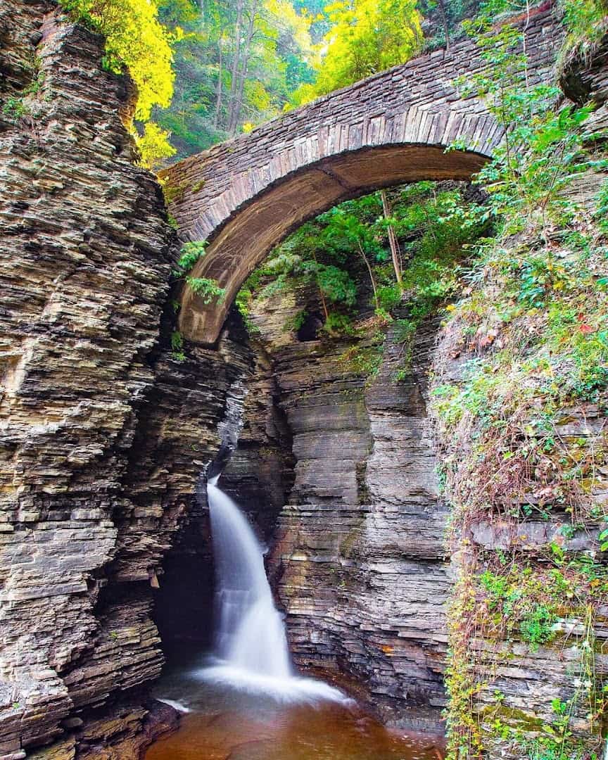 A stone arch bridge above a waterfall in the gorge at Watkins Glen State Park, New York