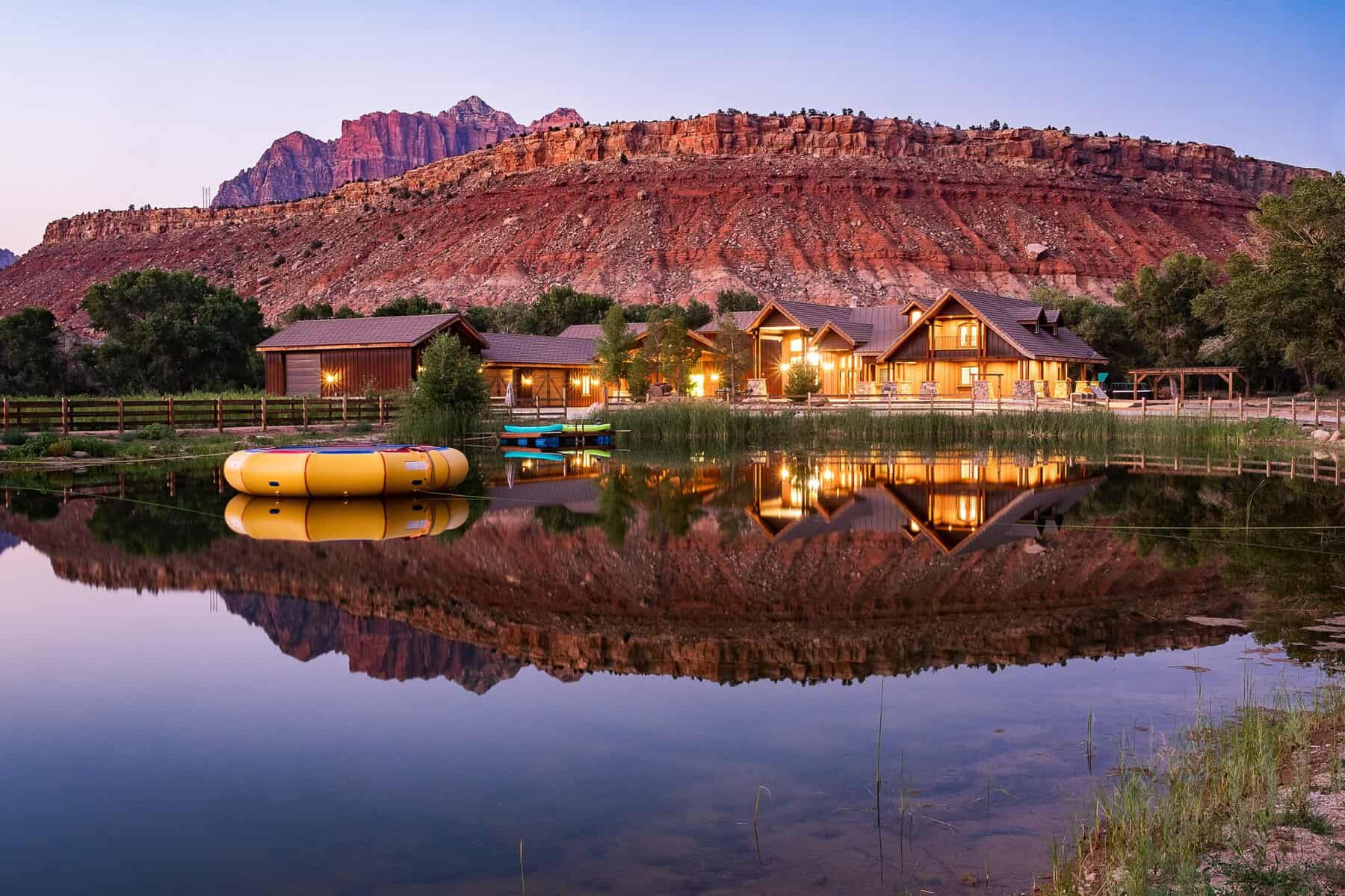 Lodge reflected in a pond beneath red rock cliffs at Zion Red Rock near Rockville, Utah