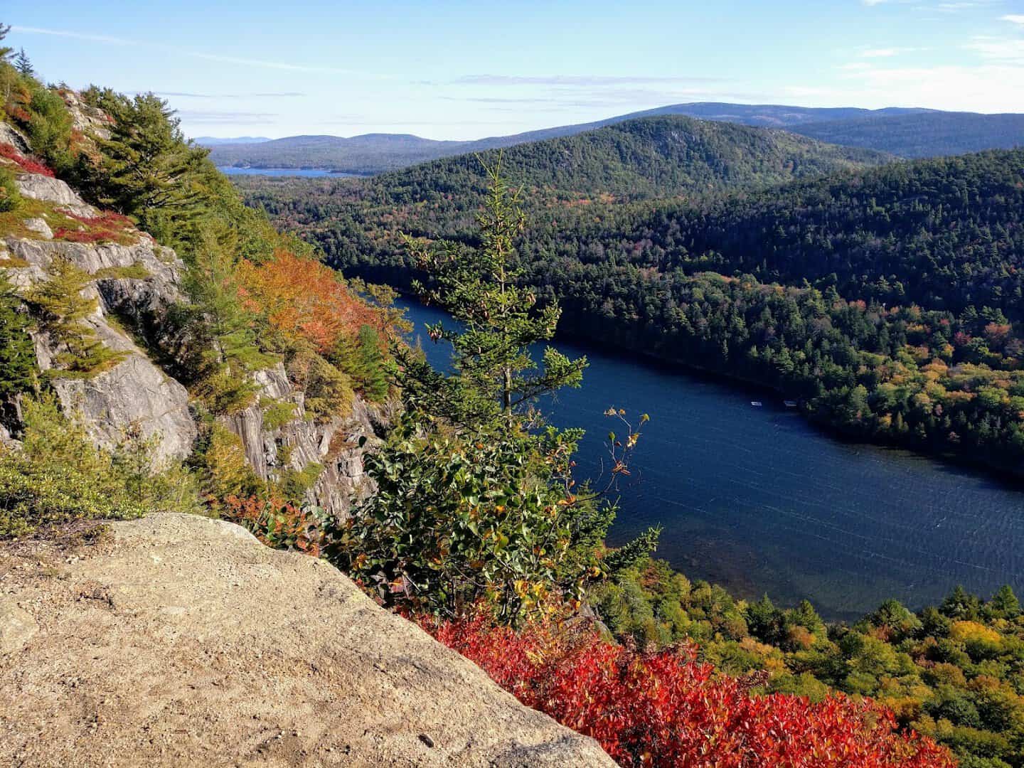 Autumn foliage over a lake from a granite cliff in Acadia National Park, Maine