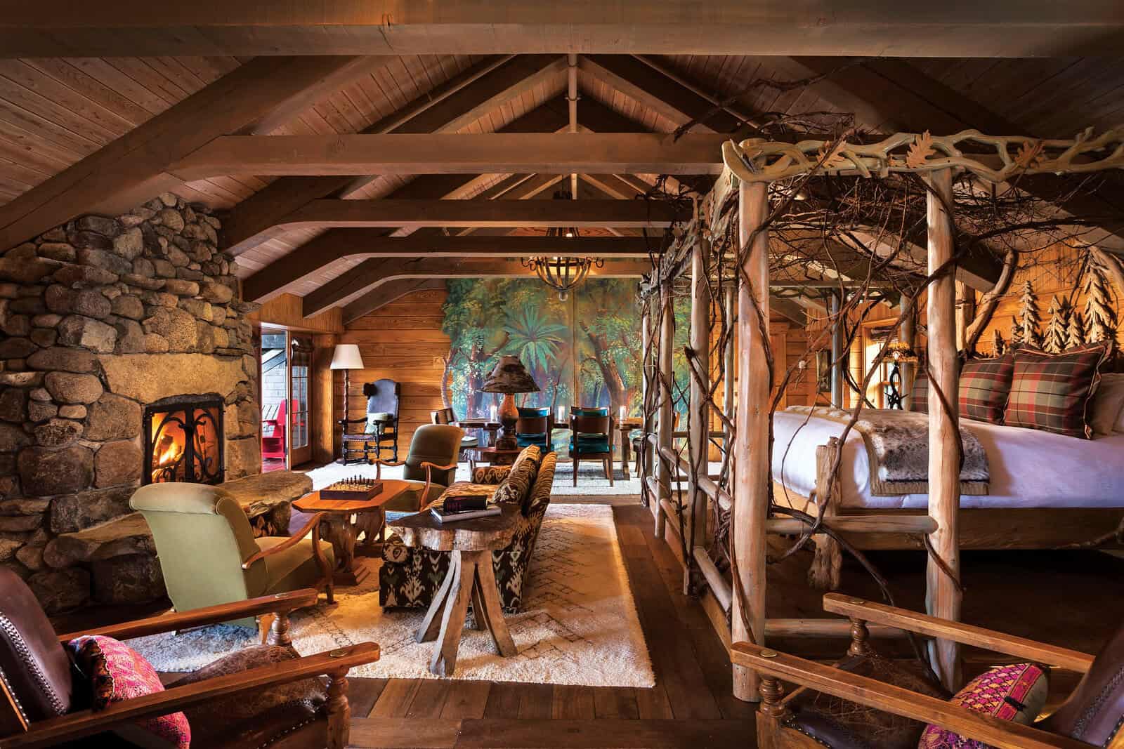 A cozy Adirondack cabin interior with a stone fireplace and hand-carved bed at Lake Placid Lodge, Lake Placid, New York