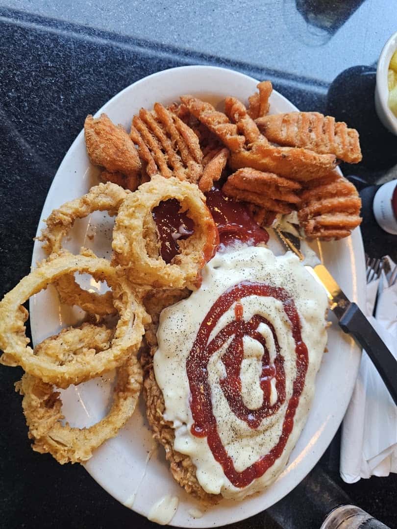 A chicken fried plate with cream gravy, onion rings and waffle fries at the Airport Diner in Fredericksburg, Texas
