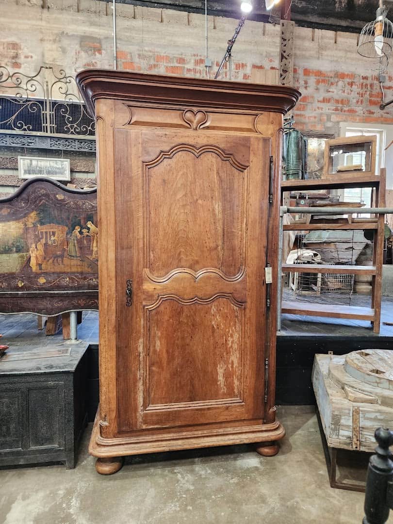 Tall antique French walnut armoire on the warehouse floor at Carol Hicks Bolton Antiques in Fredericksburg