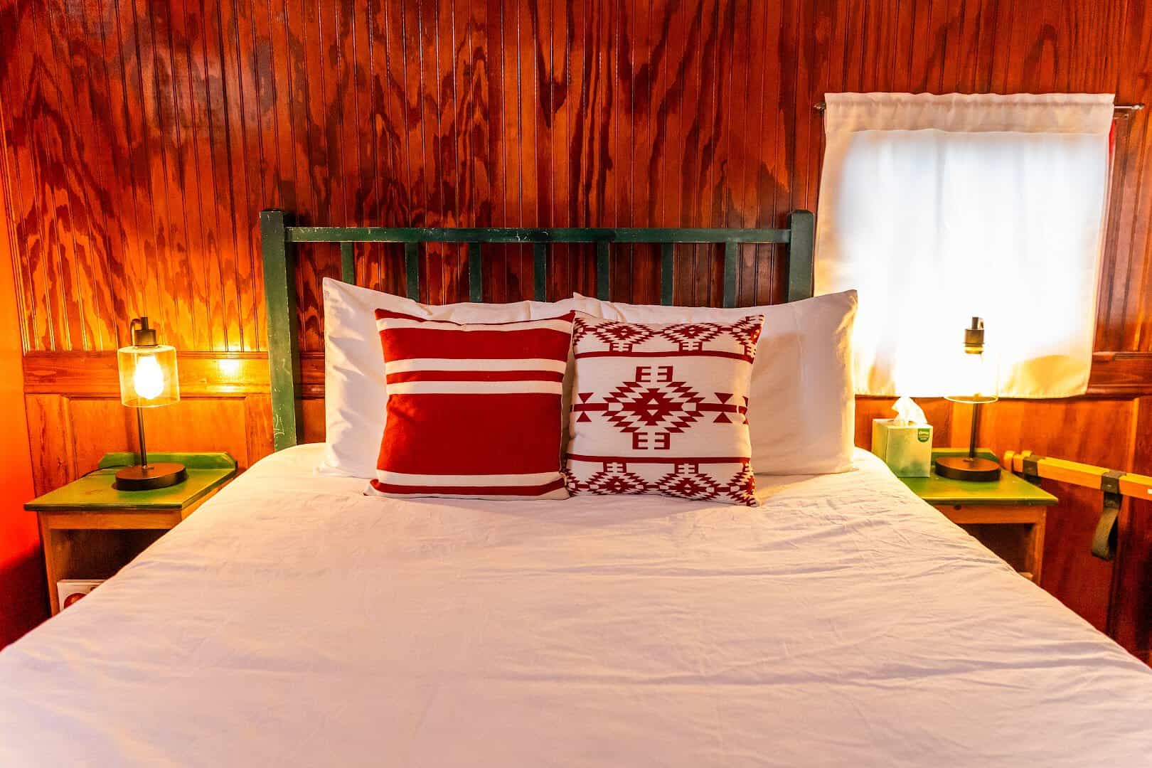 Queen bed inside a wood paneled caboose room at The Antlers Inn