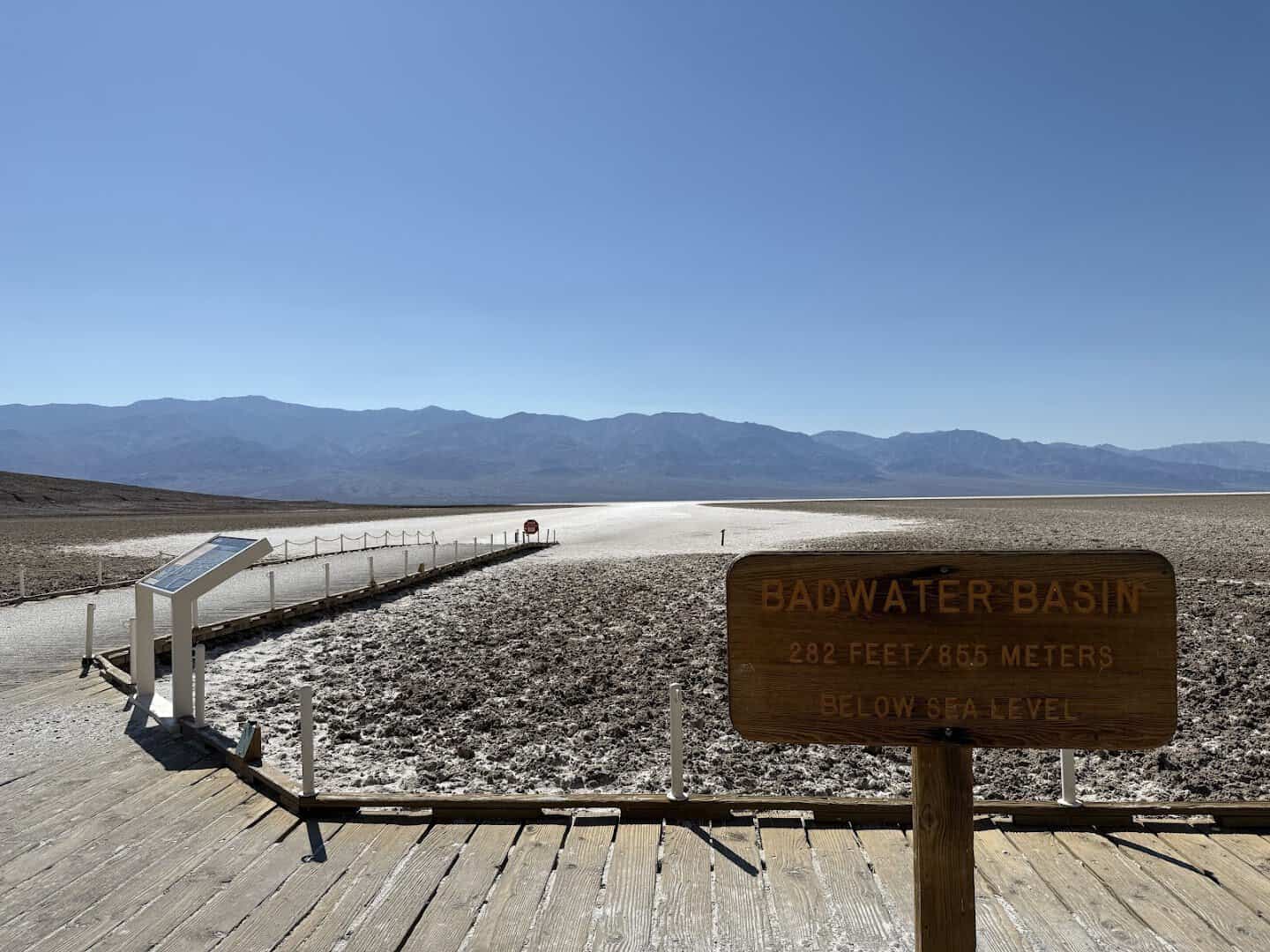 The Badwater Basin sign and white salt flats below sea level in Death Valley, California
