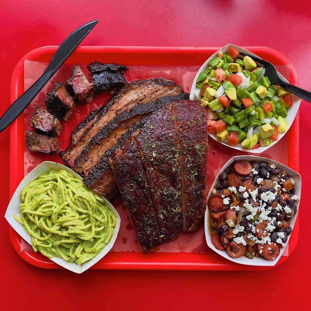 Sliced brisket, sausage and esquites on a red tray at Barbs B Q in Lockhart, Texas