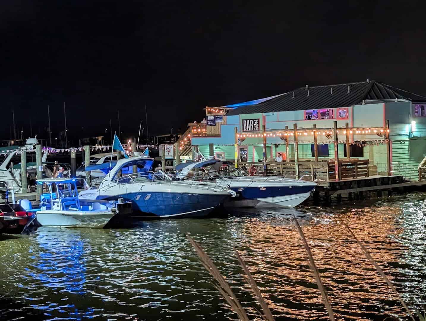 Boats docked at night beside the Barge 295 floating bar in Seabrook, Texas