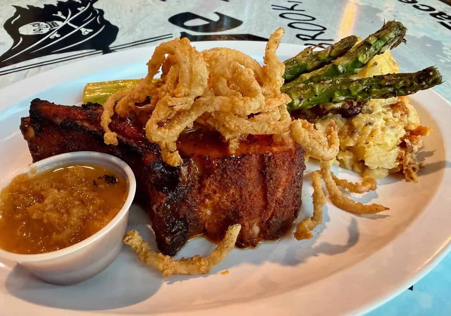 Grilled pork chop plate with crispy onions and asparagus at Barge 295 in Seabrook, Texas