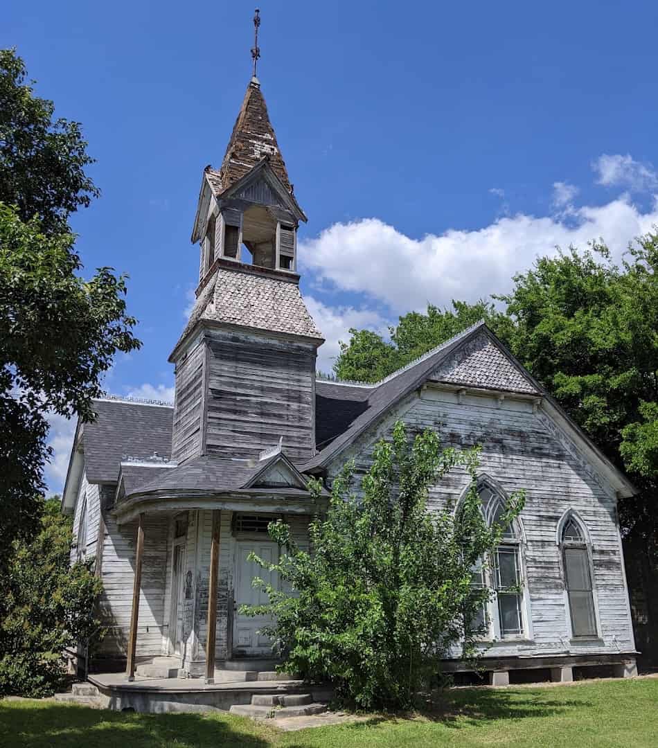 Weathered white wooden church with a bell tower in Bartlett Texas