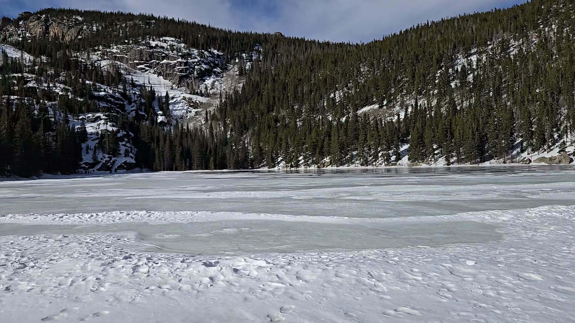 Frozen, snow-covered Bear Lake below forested slopes in Rocky Mountain National Park, Colorado, in winter