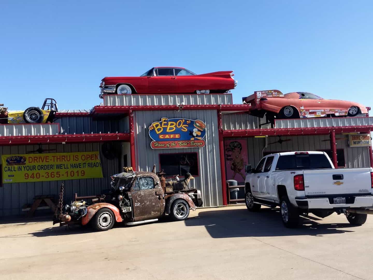 The Bebo's Cafe storefront on Highway 377 with classic cars displayed on the roof in Pilot Point, Texas