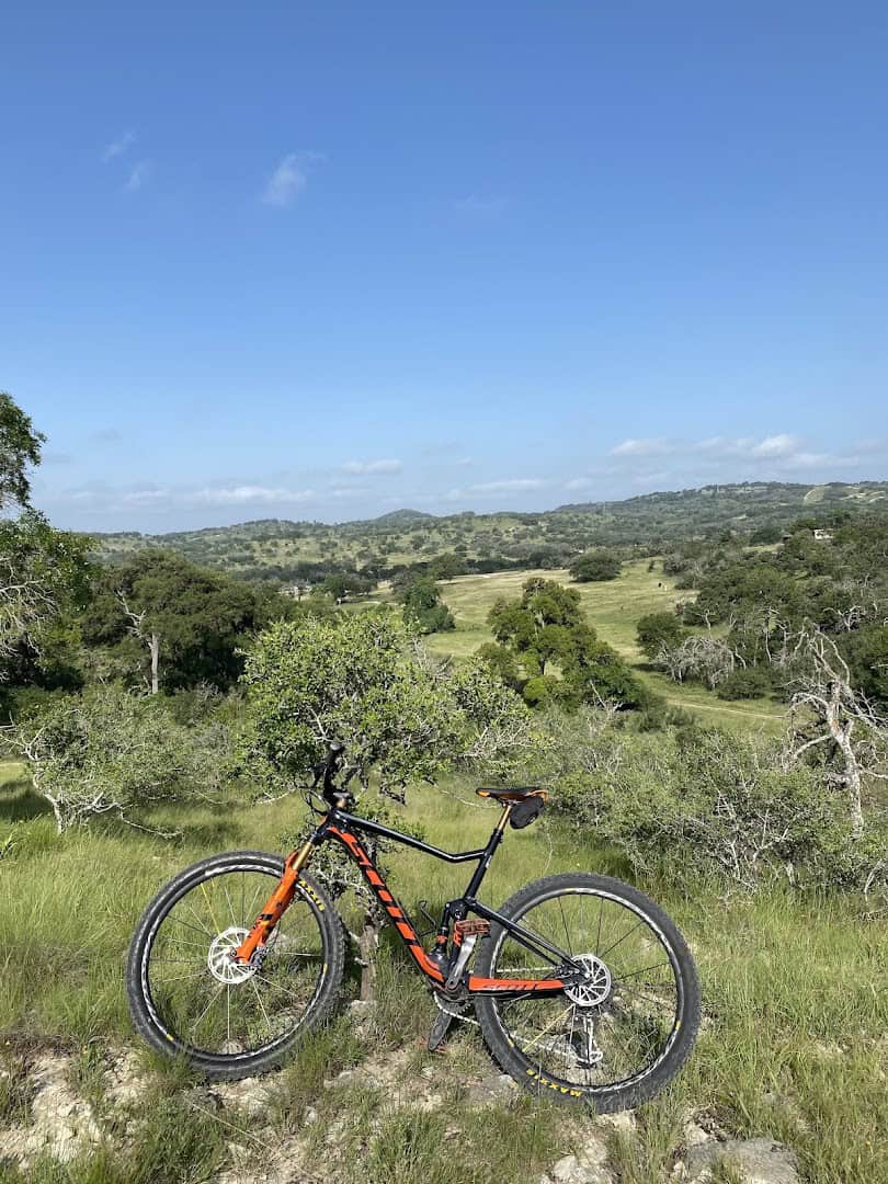 Mountain bike on a grassy trail with rolling Hill Country views at Flat Rock Ranch