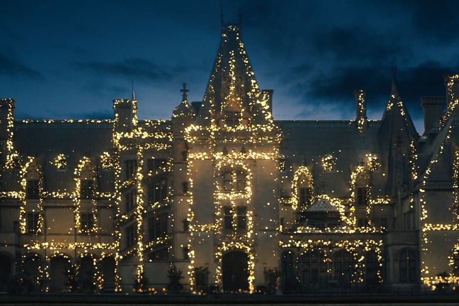 Biltmore Estate facade wrapped in warm Christmas lights at dusk, Asheville, North Carolina