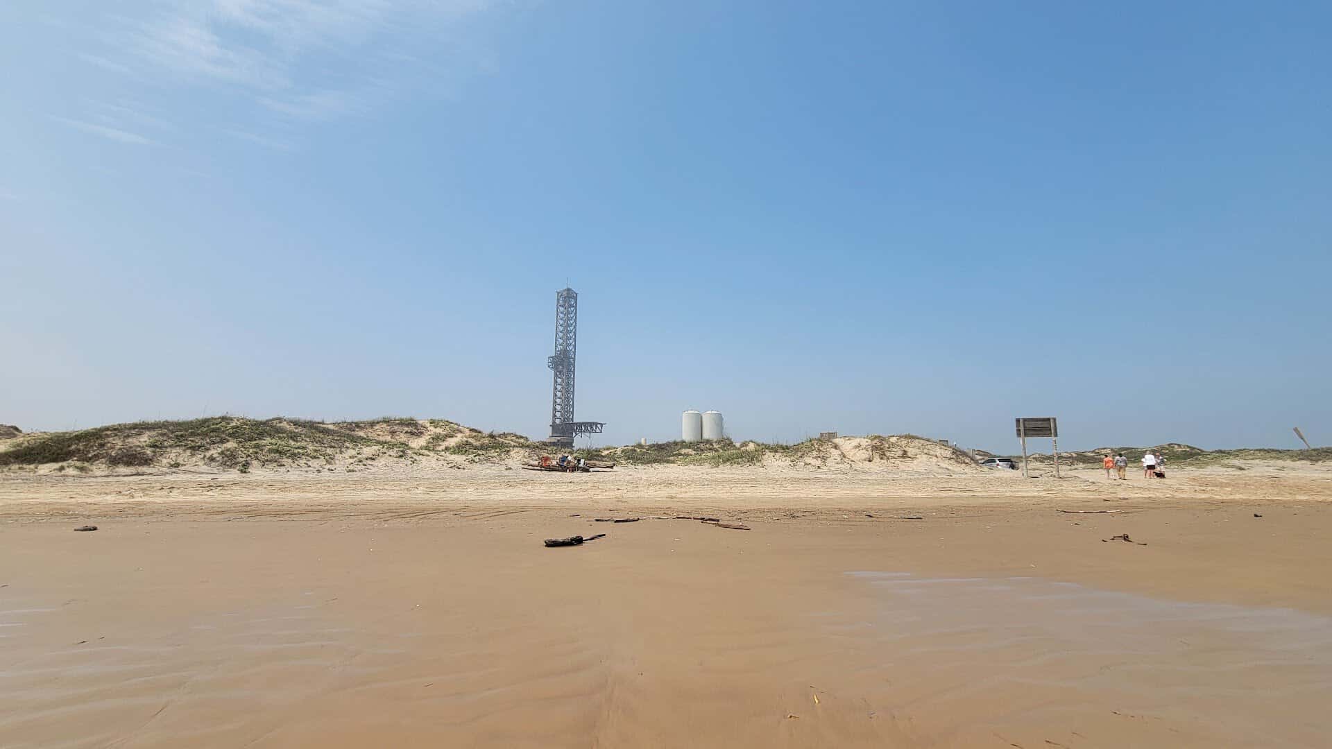 Wide open sand at Boca Chica Beach near Brownsville, Texas, with a SpaceX launch tower on the horizon