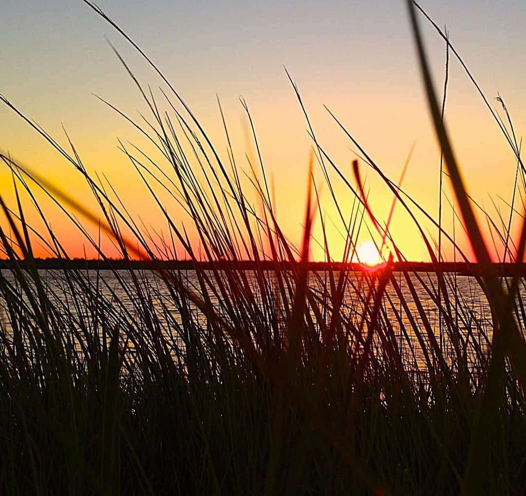 Sunset over the water seen through marsh grass on the Bolivar Peninsula