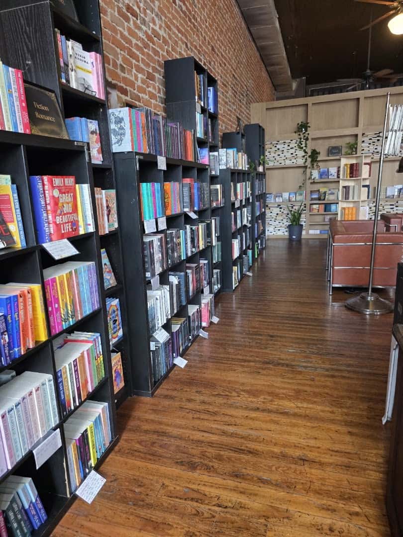 Aisle of book-lined shelves leading to the reading lounge at The Painted Porch Bookshop in Bastrop, Texas