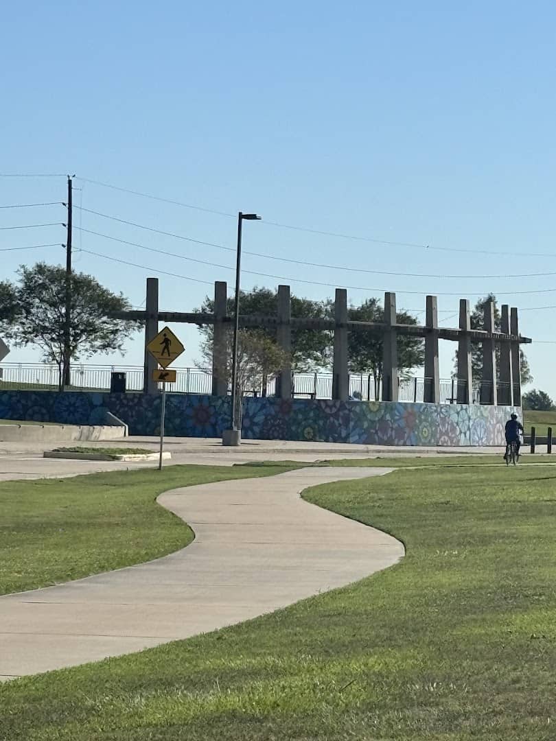 Cyclist riding the paved trail past the overlook at Brazos River Park in Sugar Land, Texas