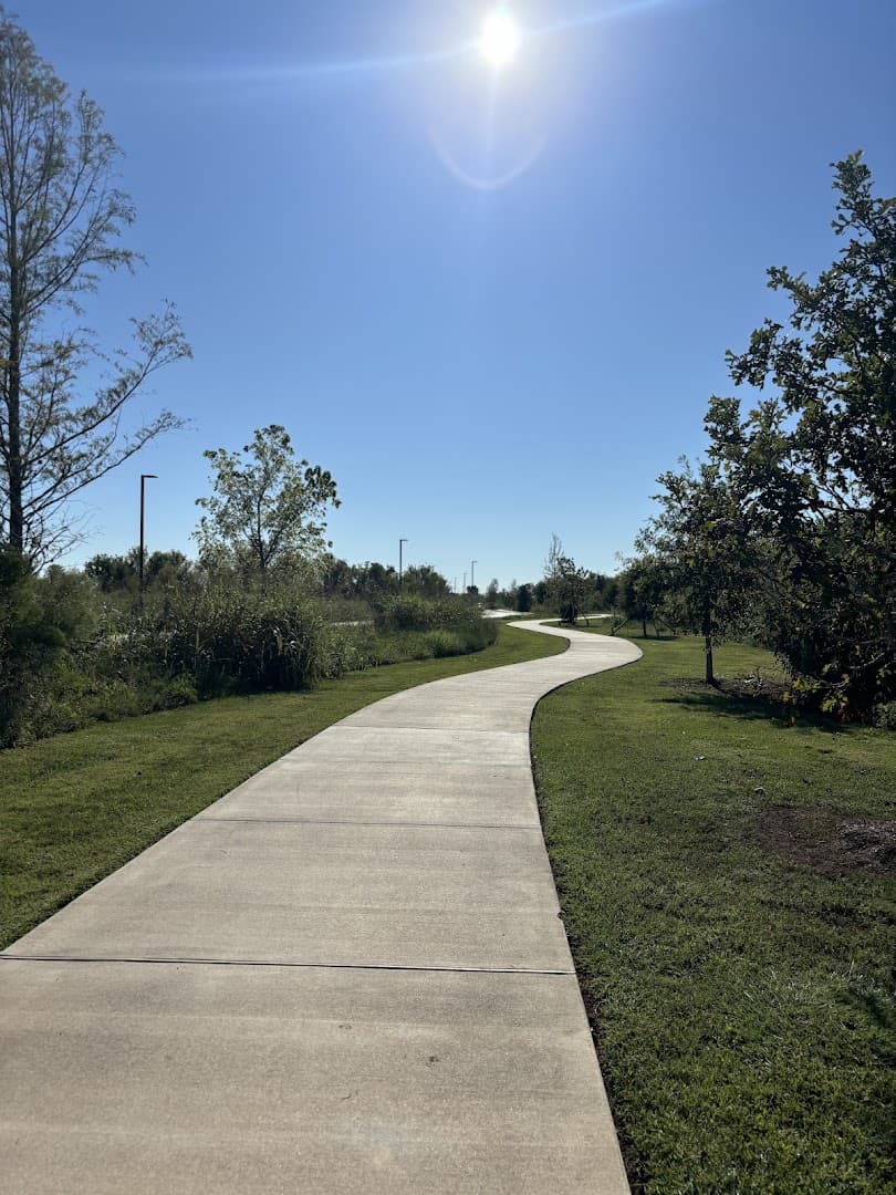 Winding paved trail through green fields at Brazos River Park in Sugar Land, Texas