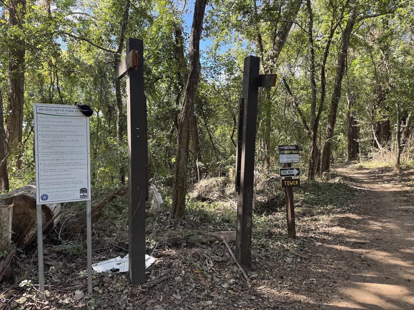 Shaded dirt trail with a marker through river-bottom woods at Brazos River Park in Sugar Land, Texas