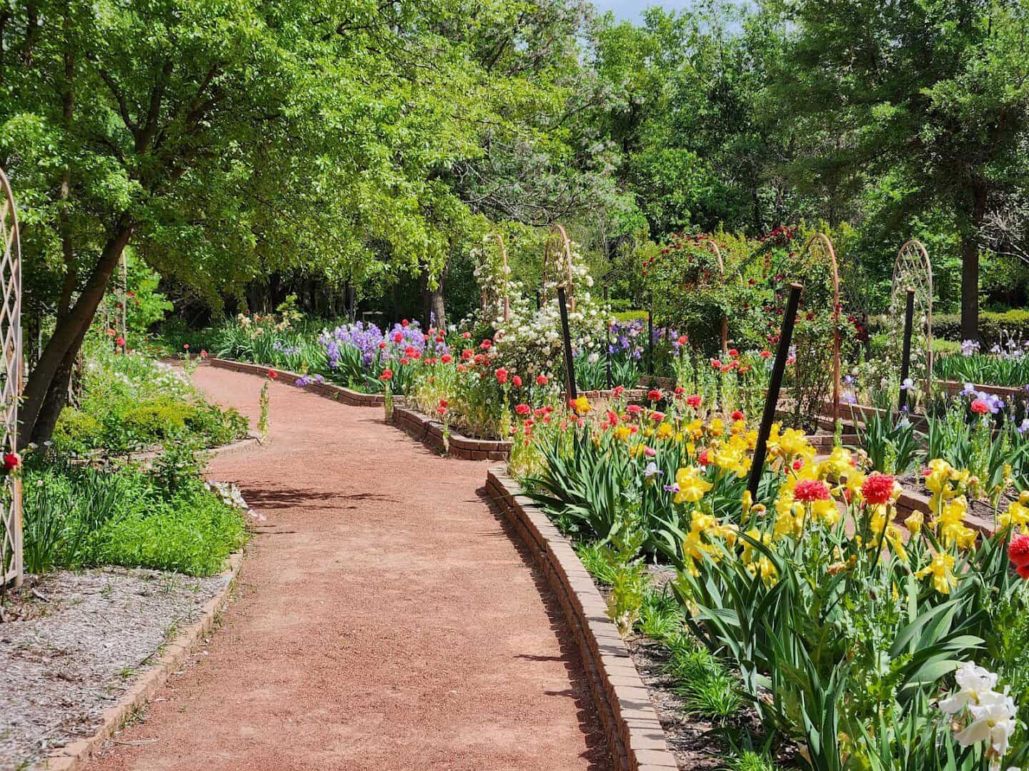 Brick path lined with colorful flower beds at Clark Gardens in Weatherford, Texas