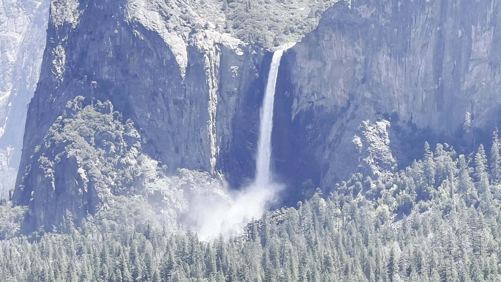 Bridalveil Fall and snow-frosted forest in Yosemite Valley, Yosemite National Park, California, in winter
