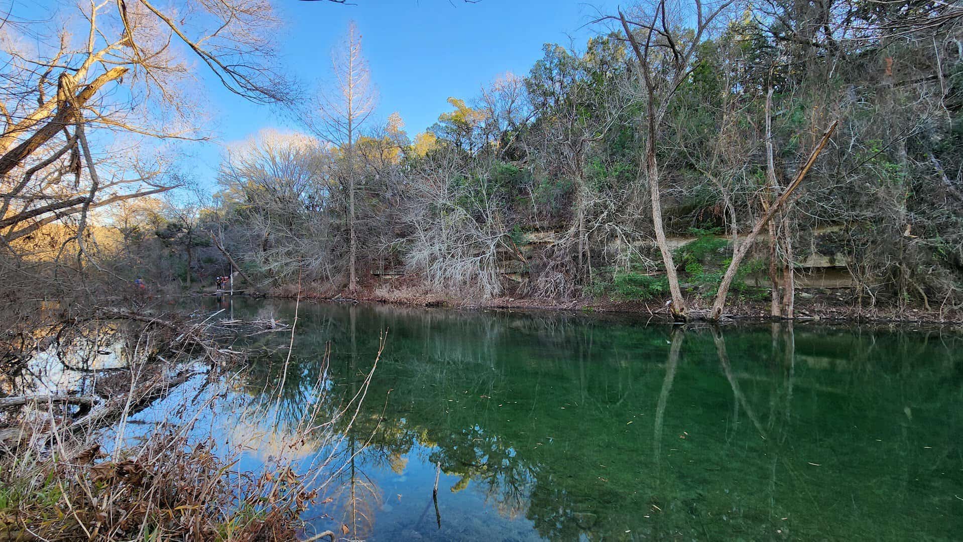 A green swimming hole reflecting the sky on Bull Creek at St. Edward's Park in Austin