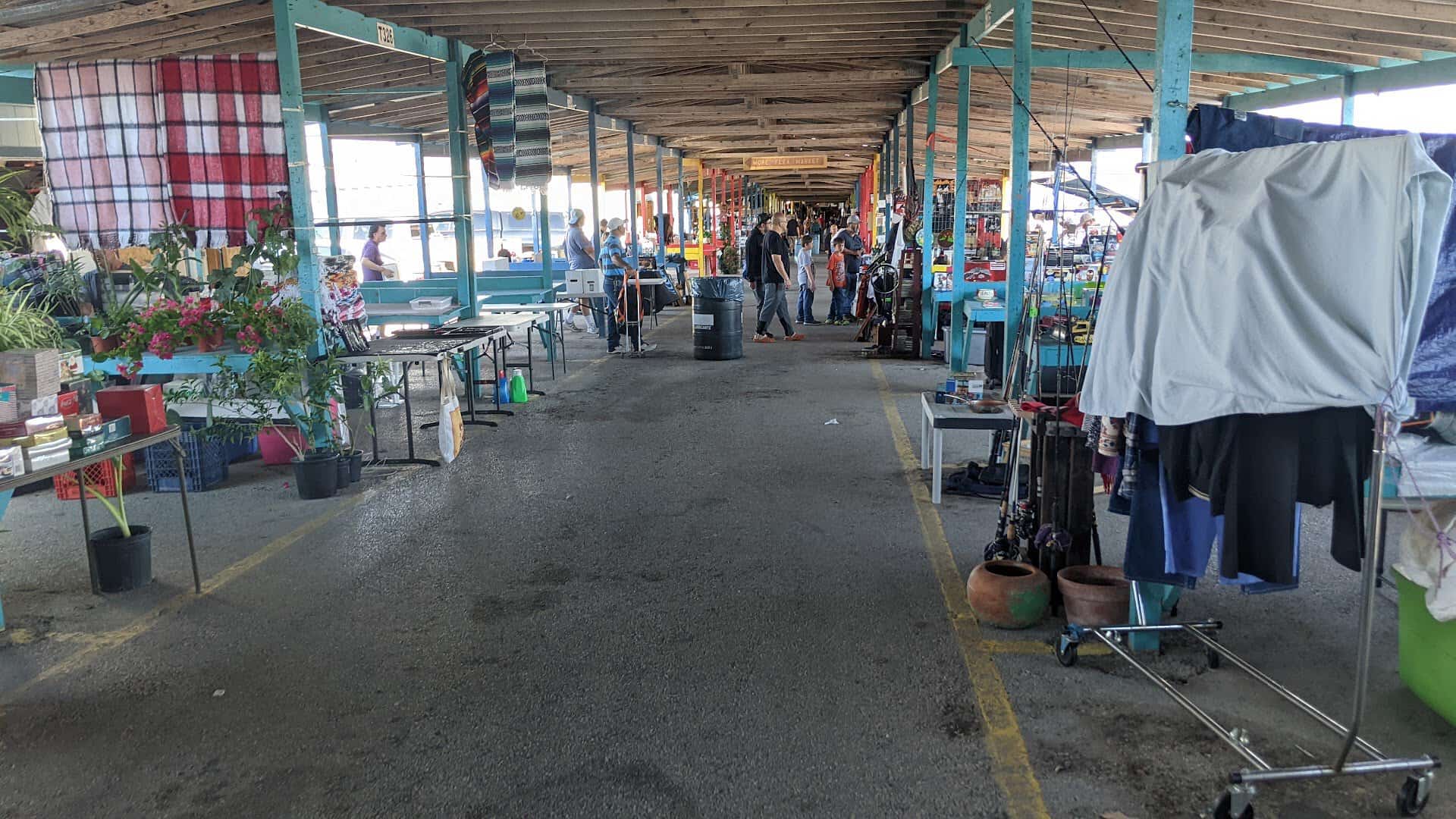 Shaded market aisle with hanging clothing at Bussey's Flea Market in Schertz, Texas