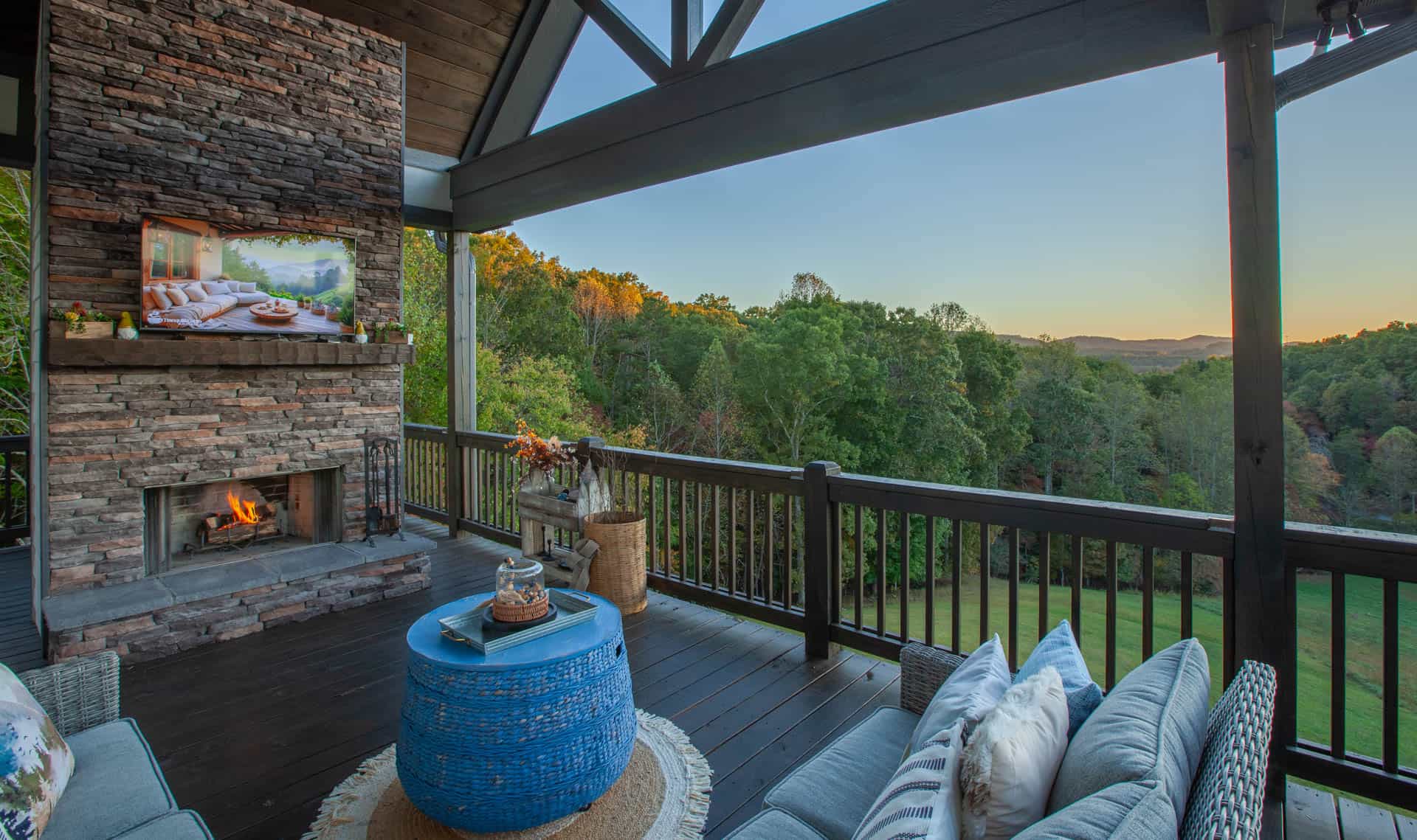 A covered cabin porch with an outdoor stone fireplace and mountain views at Blue Ridge, Georgia