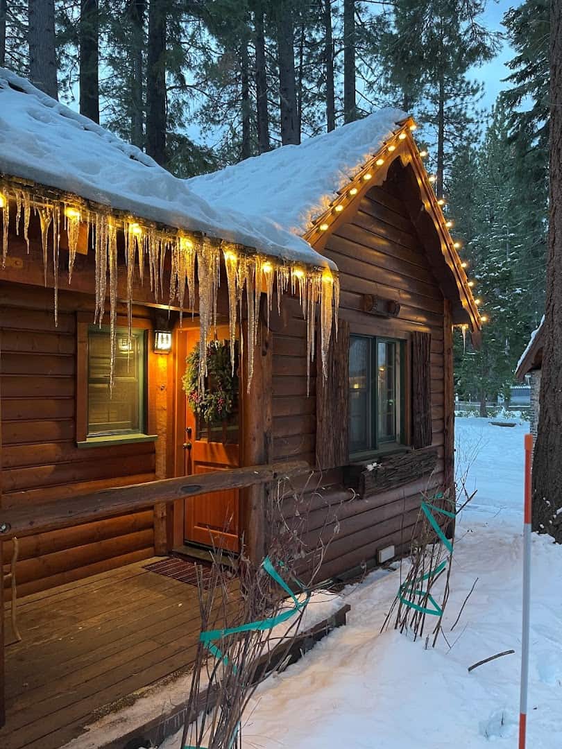 Knotty-pine cabin glowing with lights and icicles in the snow, The Cottage Inn, Tahoe City, California