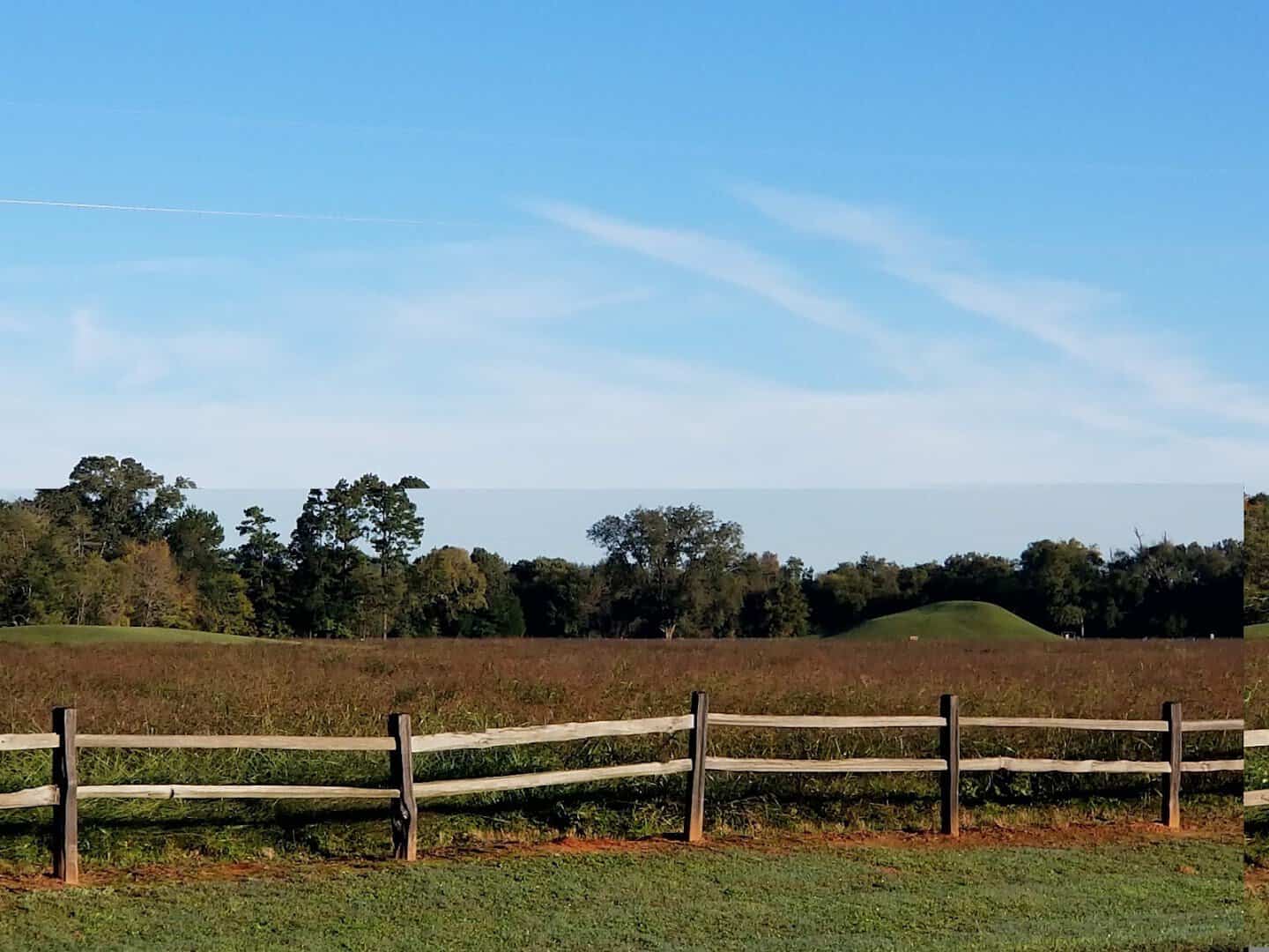 Earthen mound behind a wooden fence at Caddo Mounds State Historic Site in East Texas