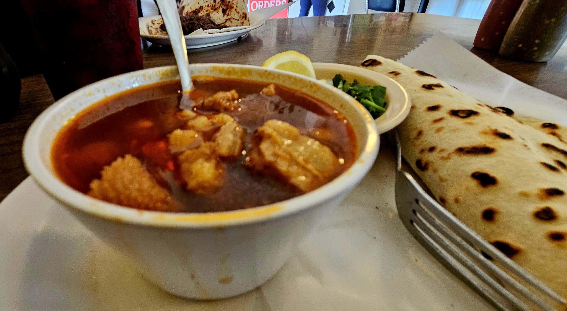 Bowl of caldo with a charred flour tortilla at Southside Barbacoa in Corpus Christi